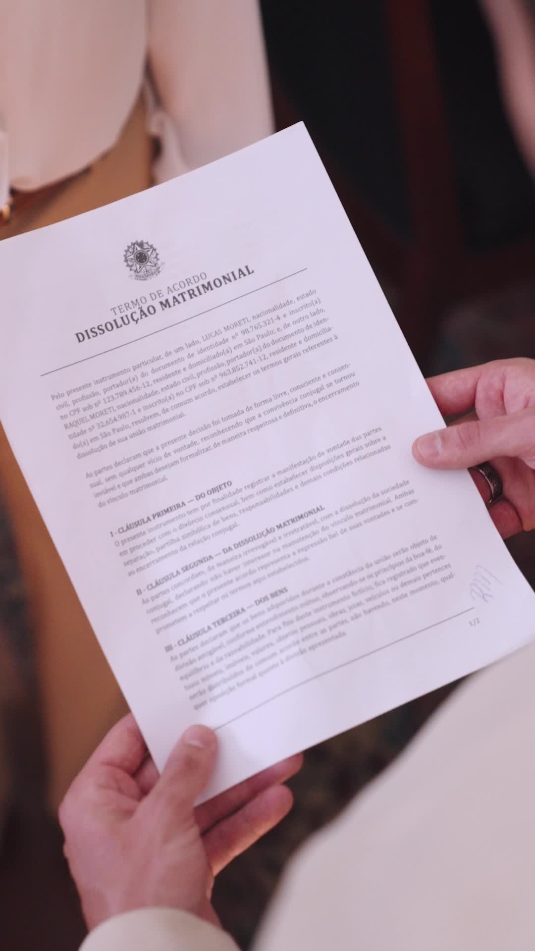 Mãos segurando um documento impresso com o título Termo de Acordo, Dissolução Matrimonial, em nome de Lucas Moreti e Raquel Moreti
