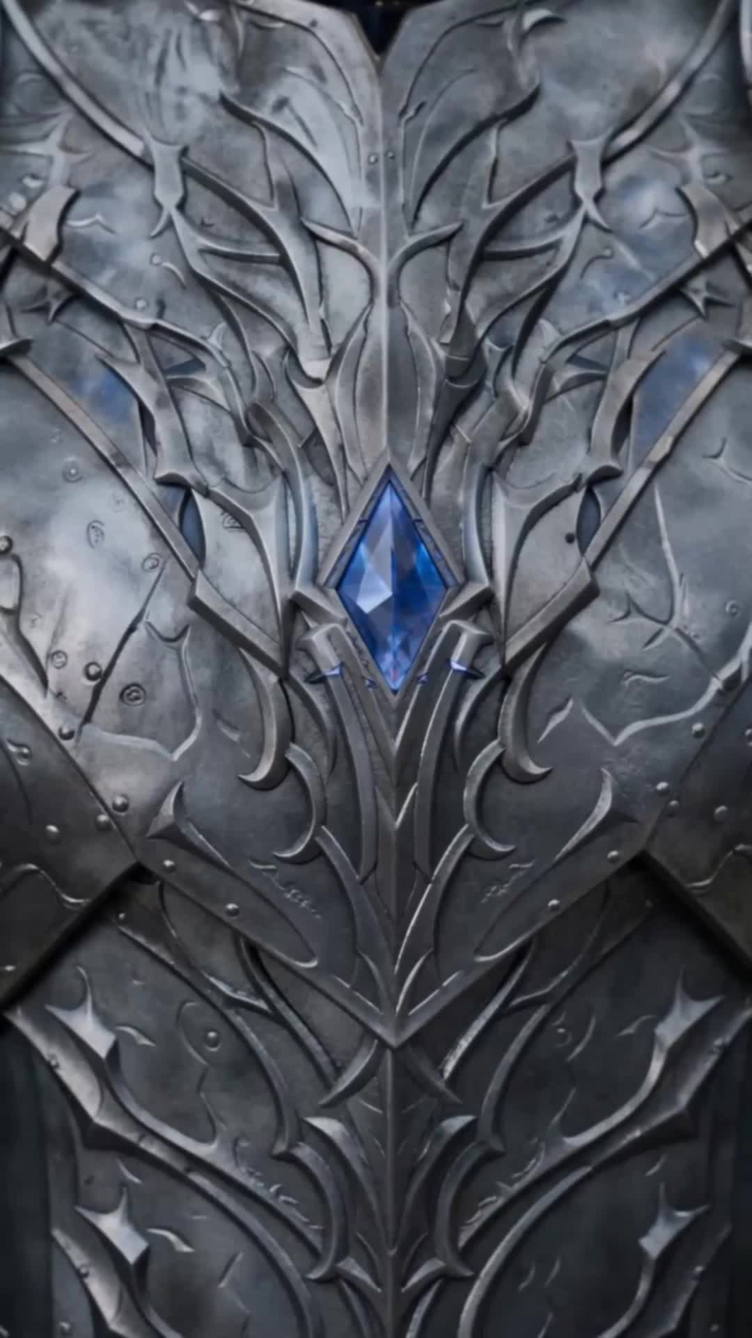 Detalhe de uma armadura prateada com relevos e uma joia azul no peito
